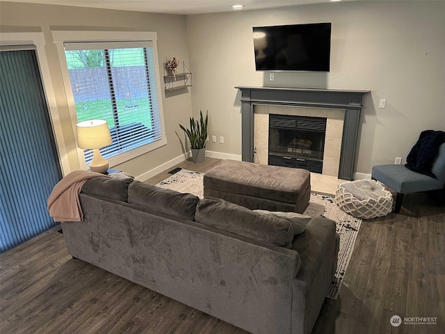 living room with wood-type flooring and a tiled fireplace