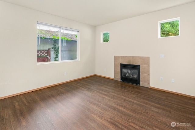 unfurnished living room featuring dark wood-type flooring, a fireplace, and a healthy amount of sunlight