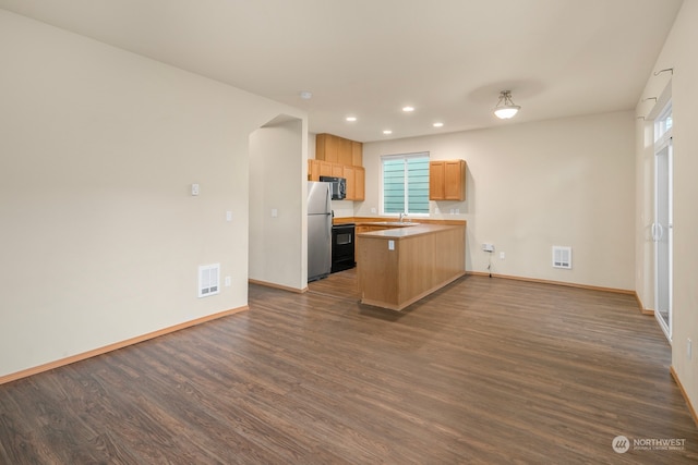 kitchen with light brown cabinetry, black appliances, sink, kitchen peninsula, and dark hardwood / wood-style floors