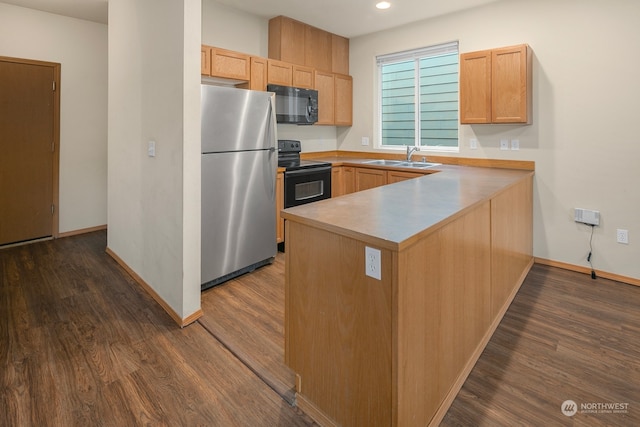 kitchen with black appliances, sink, kitchen peninsula, light brown cabinets, and dark hardwood / wood-style floors