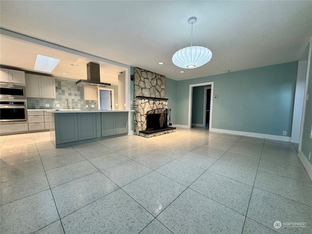 unfurnished living room featuring a stone fireplace, a textured ceiling, and a skylight