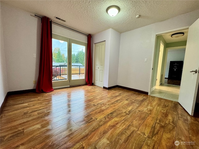 unfurnished room with hardwood / wood-style floors and a textured ceiling