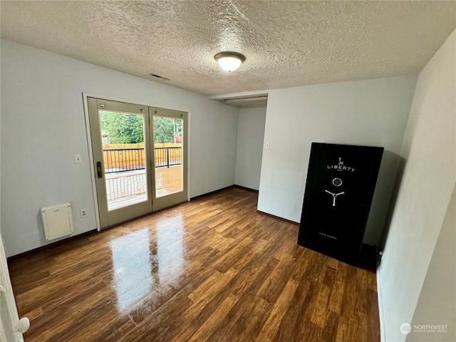 empty room featuring a textured ceiling and dark hardwood / wood-style floors