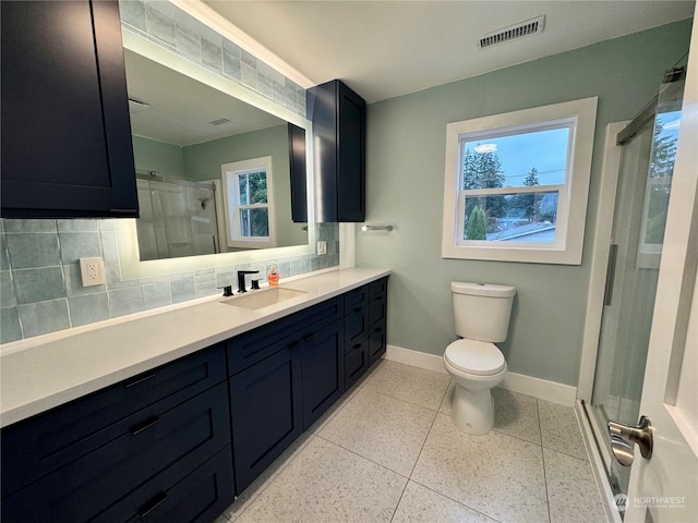 bathroom featuring decorative backsplash, a shower with door, a wealth of natural light, toilet, and vanity