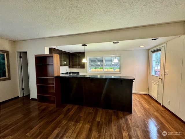 kitchen with dark brown cabinetry, a textured ceiling, dark hardwood / wood-style floors, and hanging light fixtures