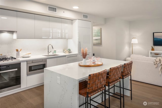 kitchen featuring appliances with stainless steel finishes, dark hardwood / wood-style flooring, a breakfast bar area, and white cabinets