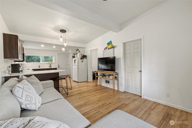 living room featuring light hardwood / wood-style floors and vaulted ceiling with beams