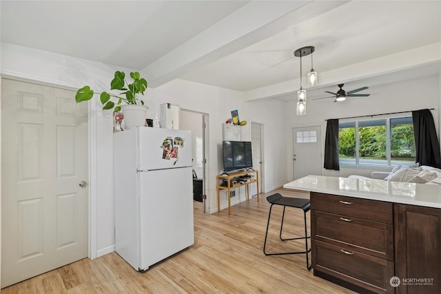 kitchen featuring beamed ceiling, a kitchen breakfast bar, white fridge, and light hardwood / wood-style floors