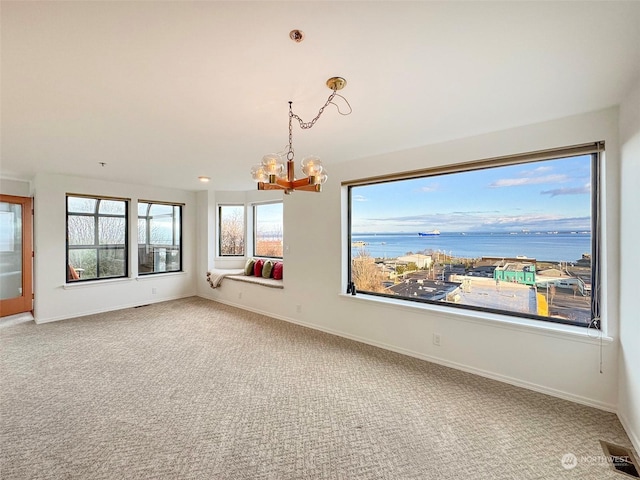 spare room featuring a chandelier, carpet, and a water view