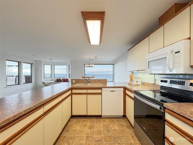 kitchen featuring kitchen peninsula, sink, white appliances, and an inviting chandelier