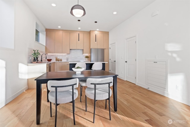 kitchen with sink, decorative light fixtures, light brown cabinetry, light hardwood / wood-style floors, and tasteful backsplash