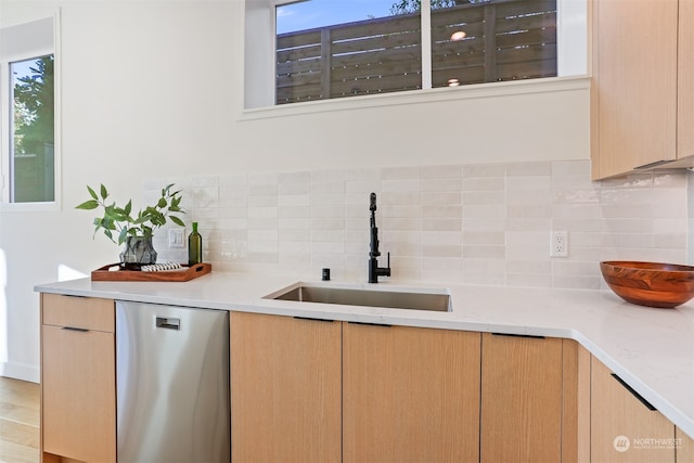 kitchen with light brown cabinetry, sink, backsplash, light hardwood / wood-style floors, and stainless steel dishwasher