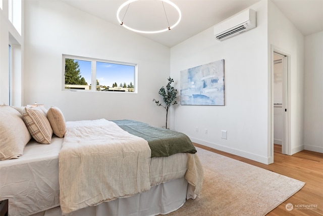 bedroom featuring vaulted ceiling, a wall mounted air conditioner, and wood-type flooring