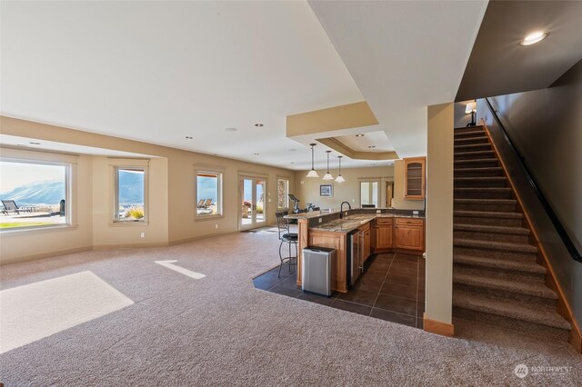 1114 S Wells, East Wenatchee, WA 98802 - kitchen featuring open floor plan, a kitchen bar, dark colored carpet, glass insert cabinets, and brown cabinets