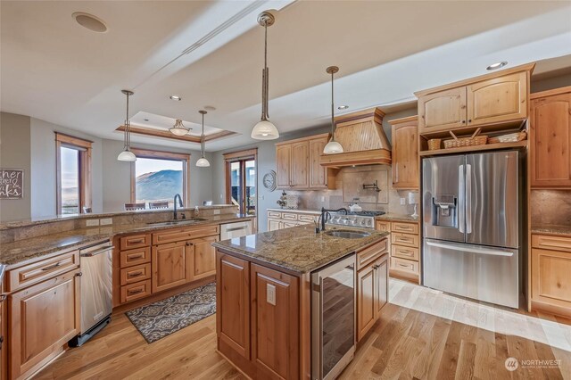 1114 S Wells, East Wenatchee, WA 98802 - kitchen featuring appliances with stainless steel finishes, wine cooler, a sink, a kitchen island with sink, and light wood-style flooring