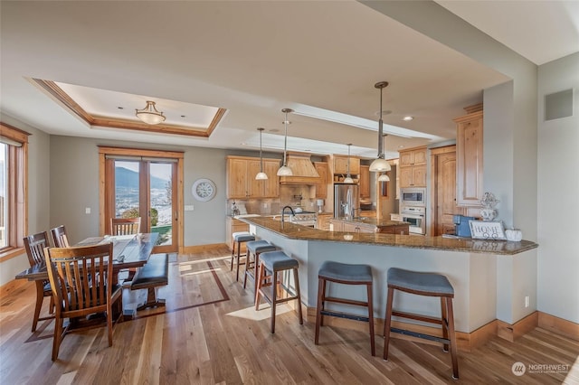 1114 S Wells, East Wenatchee, WA 98802 - kitchen featuring a tray ceiling, appliances with stainless steel finishes, wood finished floors, a sink, and custom range hood