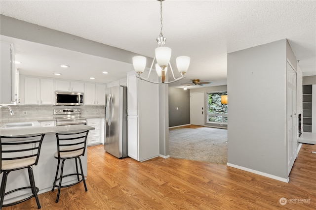 kitchen featuring a breakfast bar, sink, white cabinets, stainless steel appliances, and backsplash