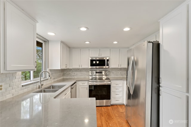 kitchen with white cabinetry, appliances with stainless steel finishes, sink, and light hardwood / wood-style flooring