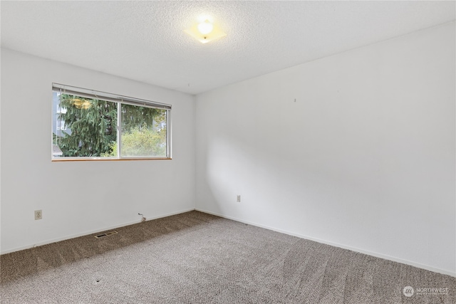 carpeted empty room featuring a textured ceiling