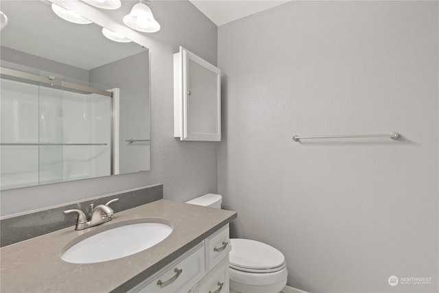 bathroom with vanity, a shower with door, and toilet