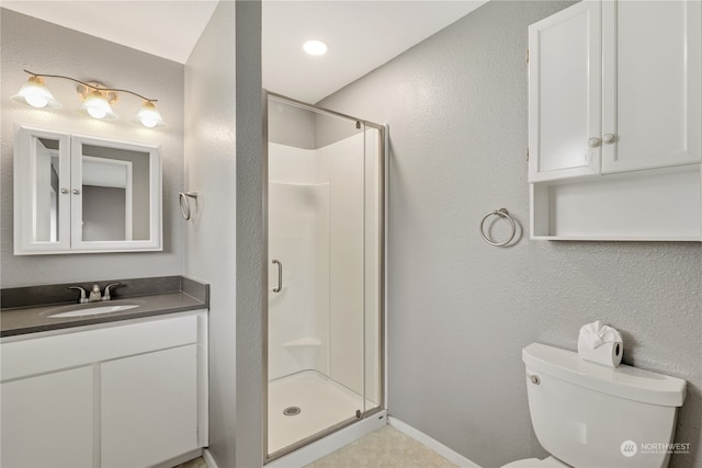 bathroom featuring vanity, a shower with shower door, and toilet