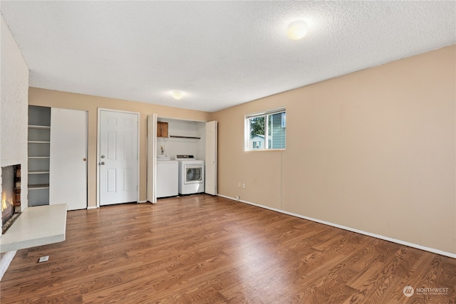 unfurnished living room featuring hardwood / wood-style floors, a fireplace, independent washer and dryer, and a textured ceiling