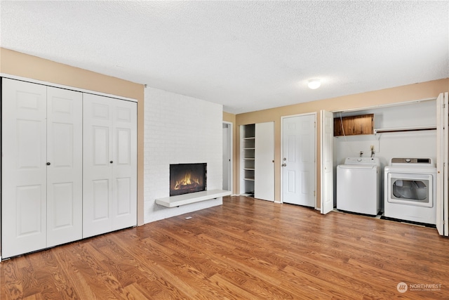 laundry area with a fireplace, independent washer and dryer, a textured ceiling, and light wood-type flooring