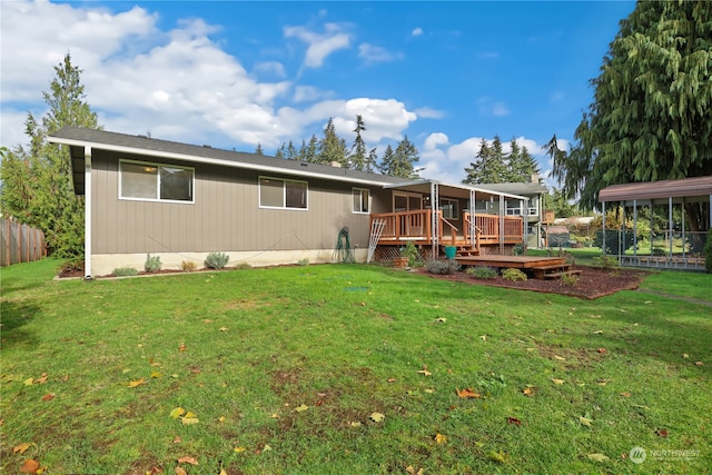 rear view of house with a wooden deck and a lawn