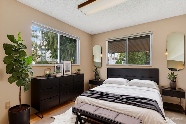 bedroom with a textured ceiling and light hardwood / wood-style flooring