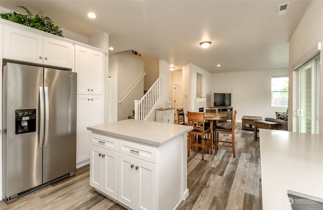 kitchen featuring stainless steel fridge, white cabinetry, light hardwood / wood-style flooring, and a center island