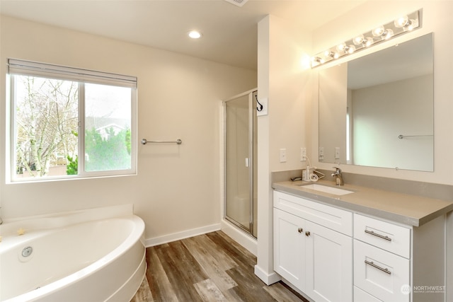 bathroom featuring vanity, hardwood / wood-style flooring, and plus walk in shower