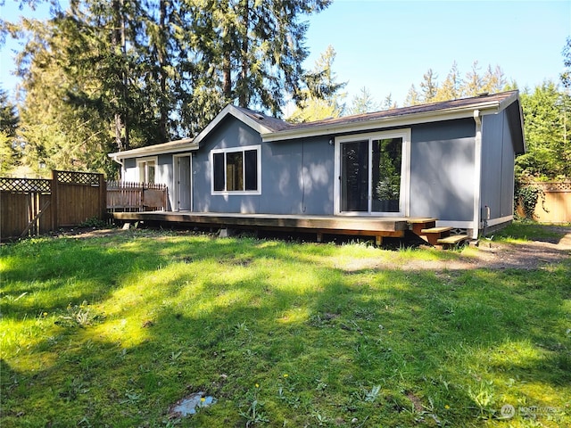 back of property featuring a deck and a lawn