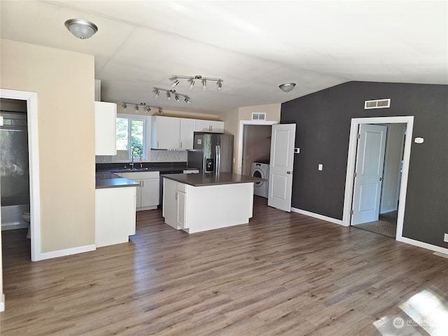 kitchen featuring washer / dryer, a kitchen island, hardwood / wood-style floors, stainless steel fridge, and white cabinets