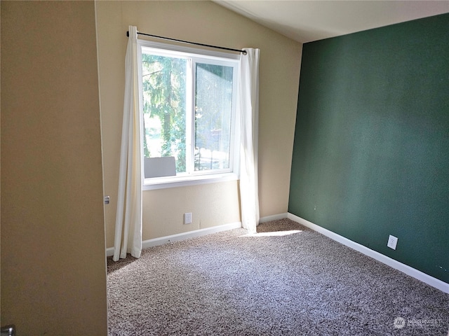 carpeted empty room featuring lofted ceiling