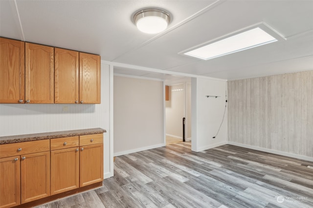 basement with light wood-type flooring and wood walls