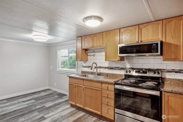 kitchen with tasteful backsplash, sink, light hardwood / wood-style floors, stainless steel appliances, and light brown cabinets