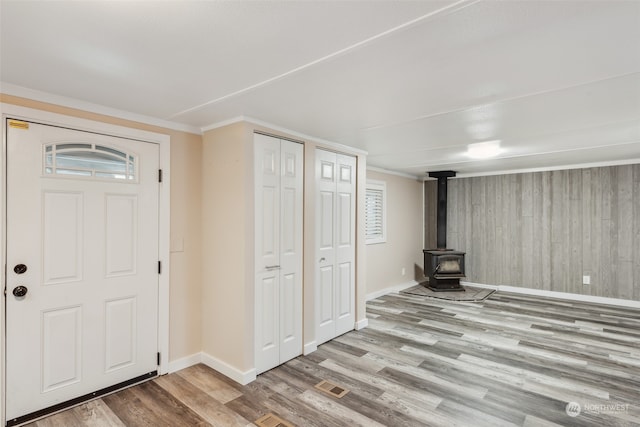 entryway with plenty of natural light, light hardwood / wood-style floors, crown molding, and wooden walls