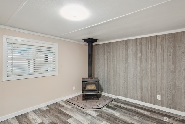 unfurnished living room featuring a wood stove, hardwood / wood-style floors, and wood walls