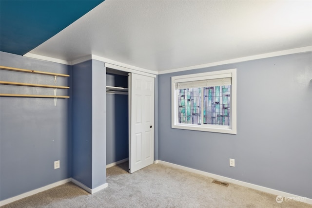 unfurnished bedroom featuring light carpet, a textured ceiling, and a closet