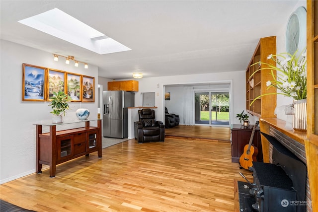 living room featuring light hardwood / wood-style flooring and a skylight