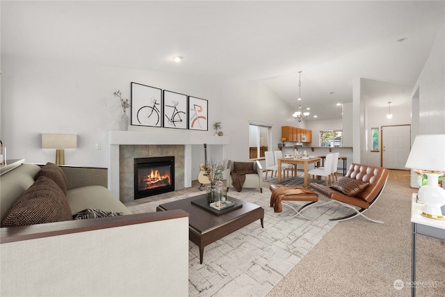 carpeted living room featuring a chandelier, a tile fireplace, and vaulted ceiling