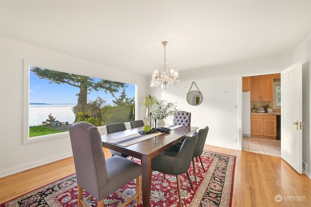 dining space featuring a chandelier, a water view, and light wood-type flooring