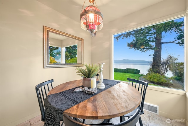 dining space with a water and mountain view, a chandelier, and light tile patterned floors