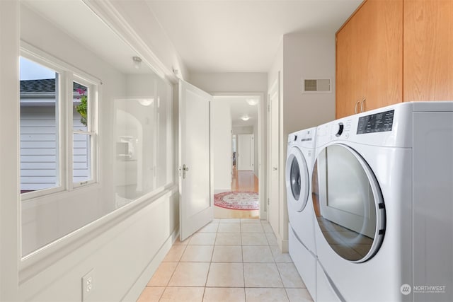 washroom with independent washer and dryer, cabinets, and light tile patterned flooring