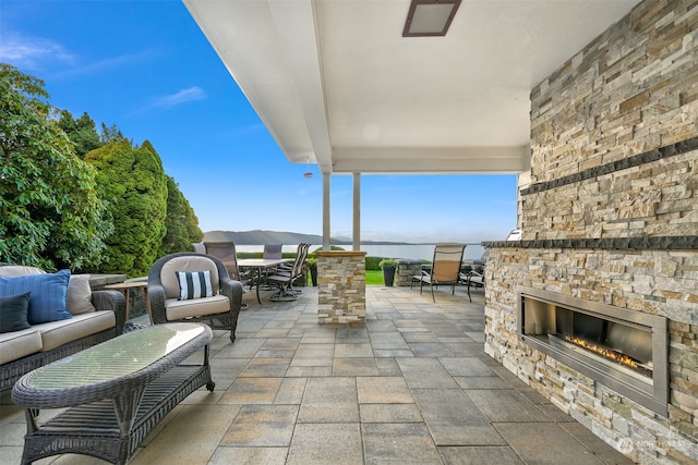 view of patio with an outdoor living space with a fireplace and a water view