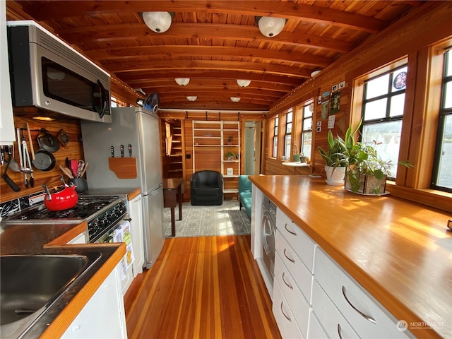 kitchen with beam ceiling, light hardwood / wood-style flooring, washer / clothes dryer, white cabinets, and wood ceiling