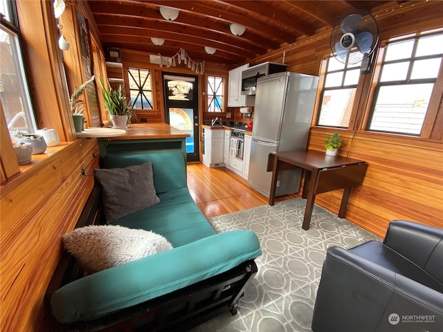 interior space featuring sink, wooden walls, light hardwood / wood-style flooring, beamed ceiling, and wood ceiling