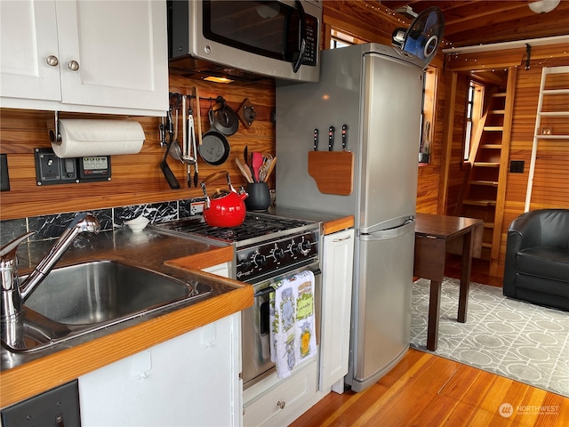 kitchen with white cabinets, appliances with stainless steel finishes, light wood-type flooring, and sink