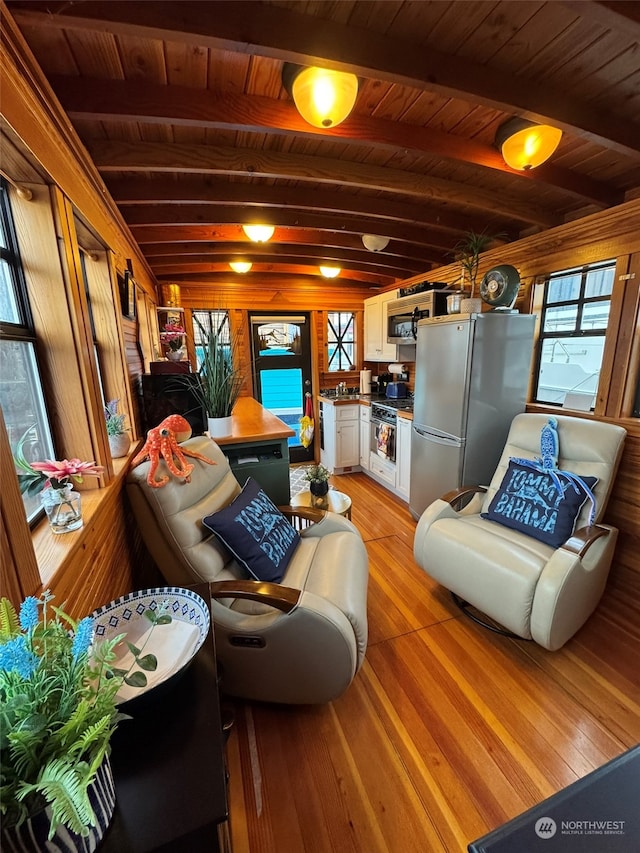 living room featuring beamed ceiling, light wood-type flooring, and wooden ceiling