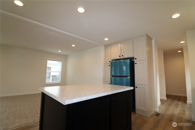 kitchen with stainless steel fridge, a center island, white cabinets, and light hardwood / wood-style flooring